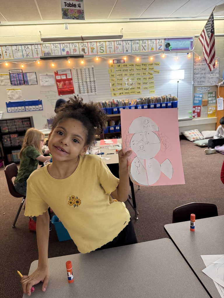 little girl holding handmade picture up in classroom