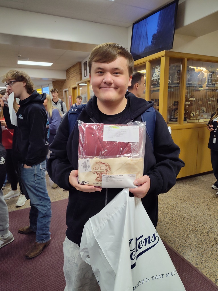 male senior with short blond hair holding package of cap and gown