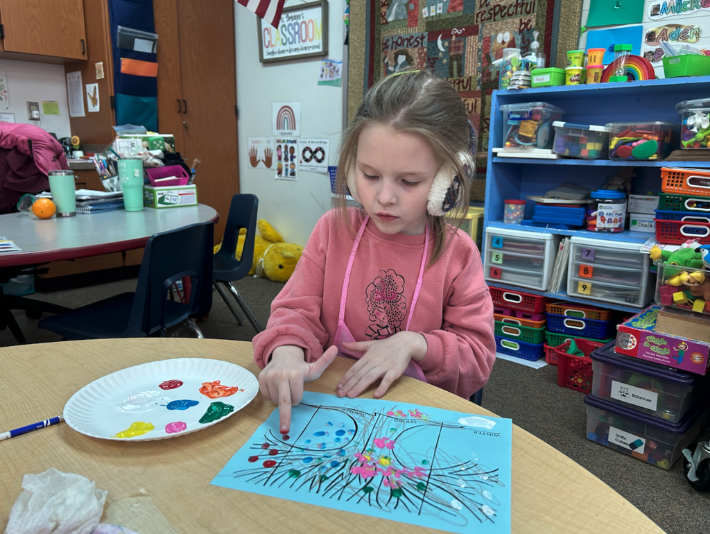 little girl finger painting the seasons at a table