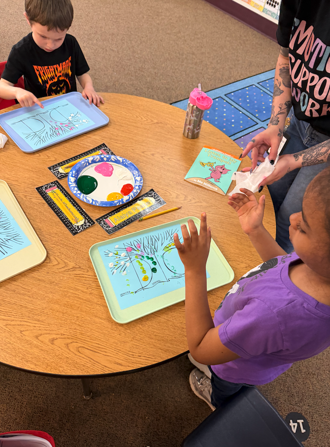 two little kids at a table finger painting seasons