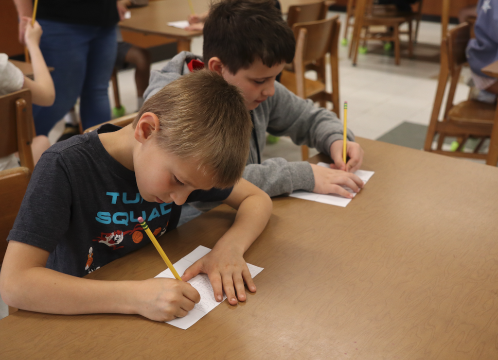 two young boy drawing on paper with pencil