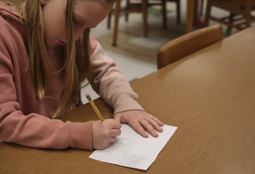 young girl drawing on paper with pencil