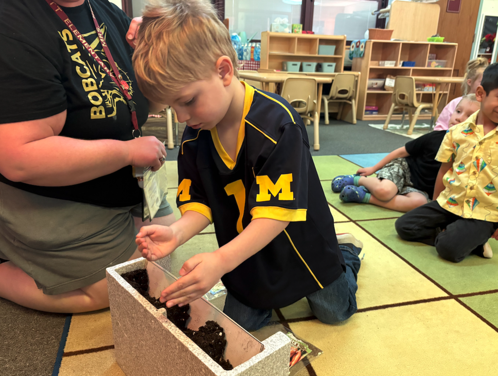 young boy putting seeds into pot