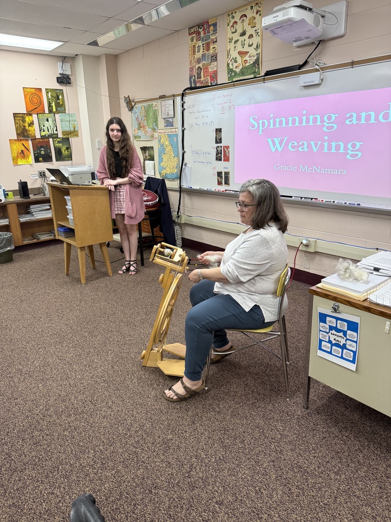 student preparing to present to class while teacher weaves