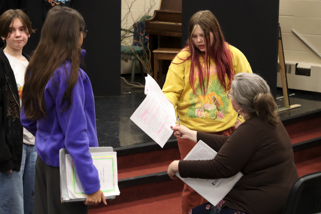 students working on script with teacher in theater class