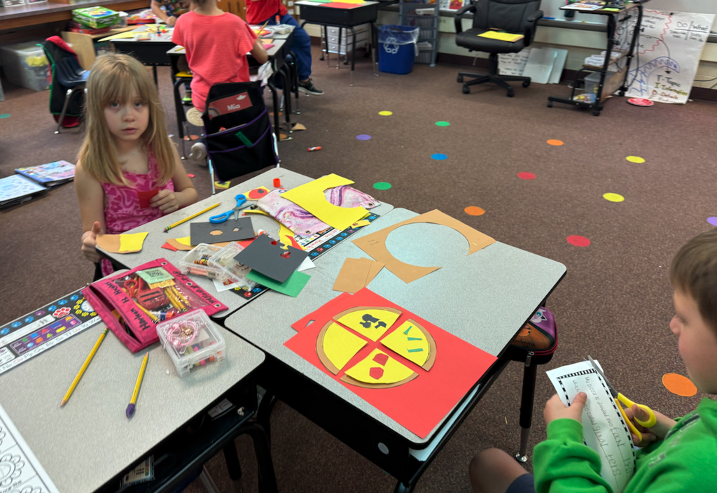 two kids working at desks creating pizzas