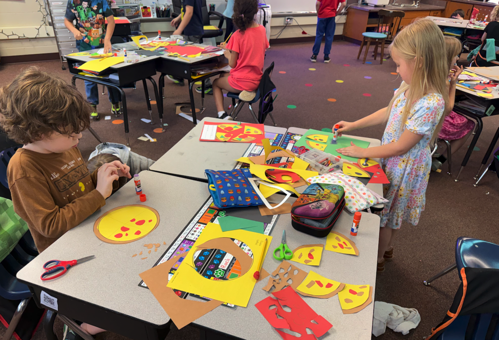 kids playing at desk putting together paper pizzas