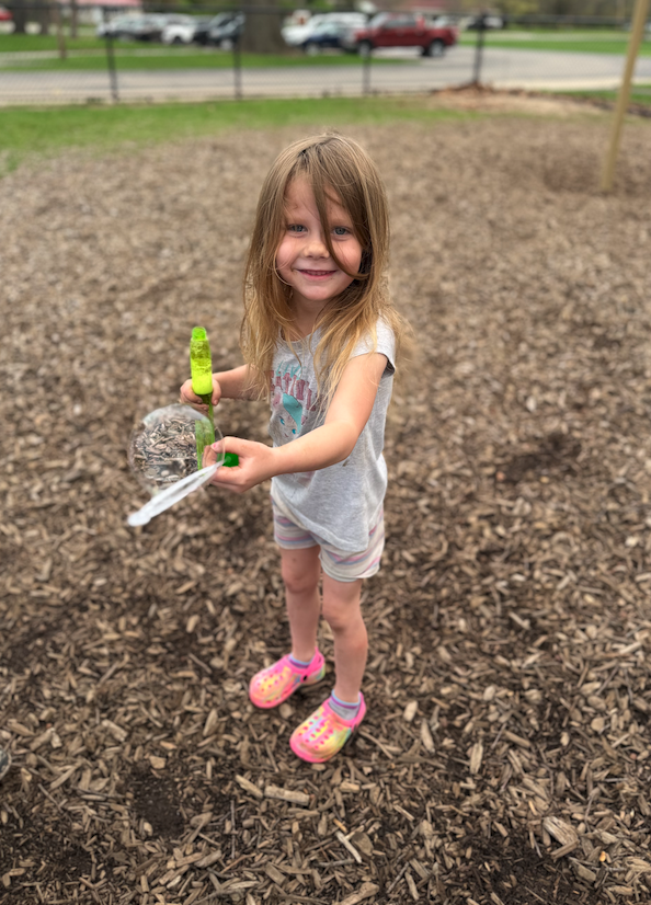 little girl on playground blowing bubbles