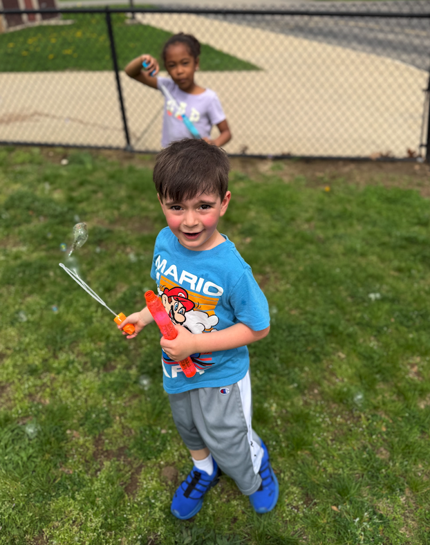 little boy blowing bubbles on the playground