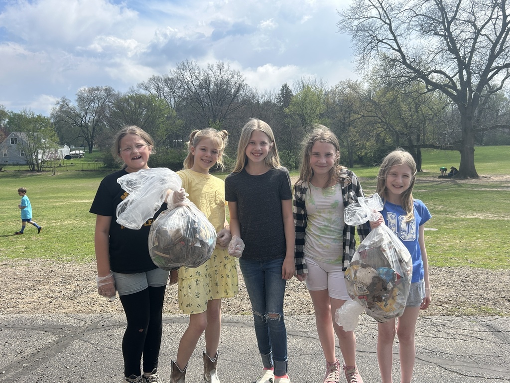 five girls on playground holding bags of trash