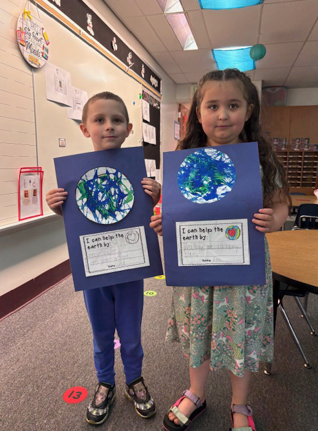 two young students holding art projects