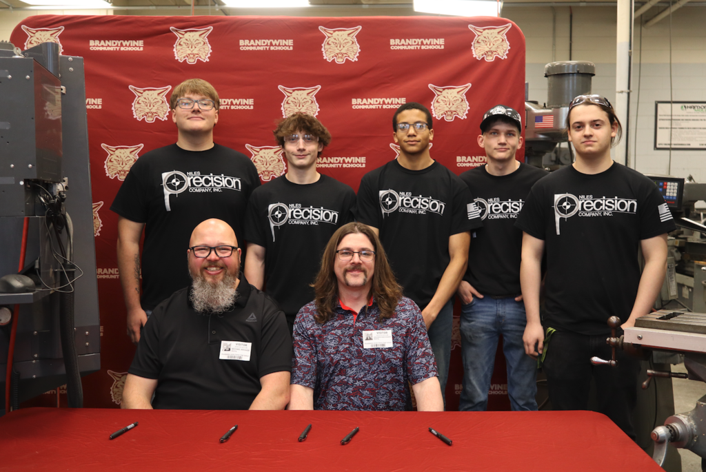 five future apprentices sitting with two men in niles precision shirts