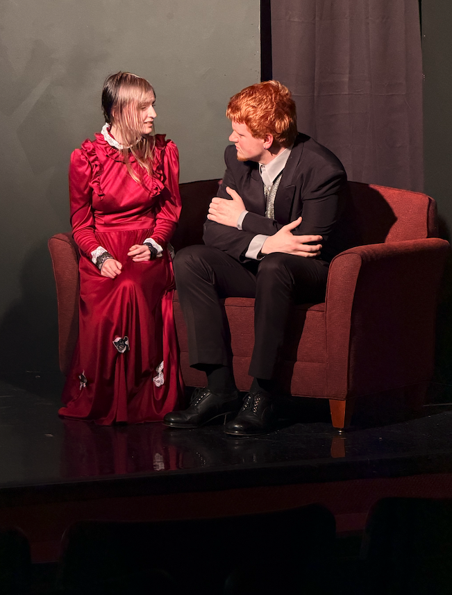 actor and actress sitting on stage 
