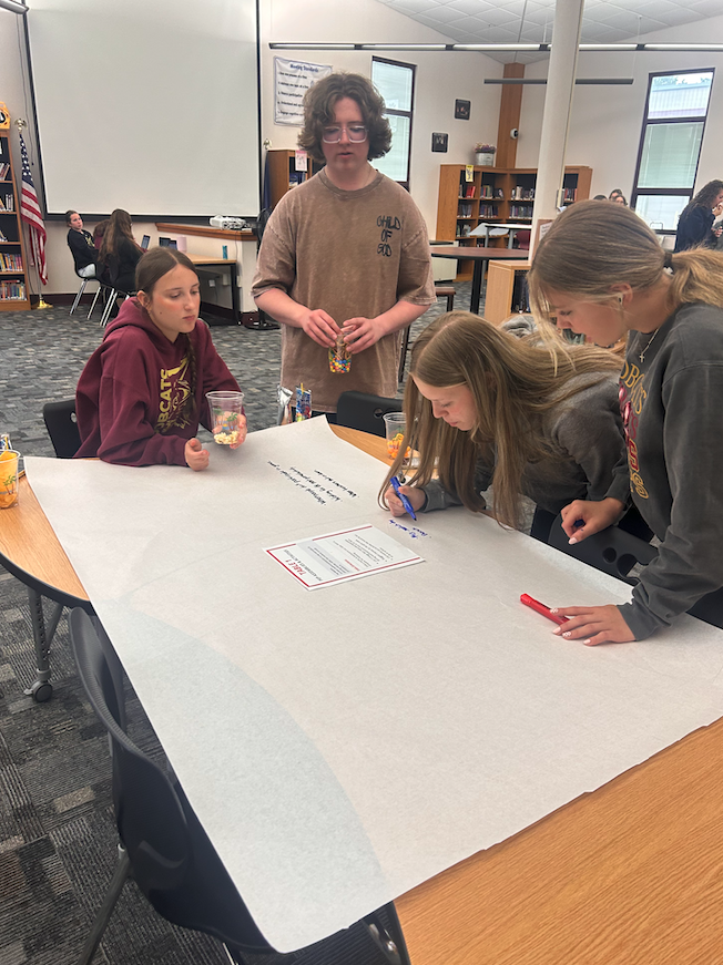 four kids standing at a table writing