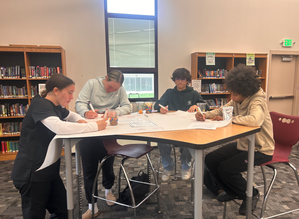 four kids standing at a table writing