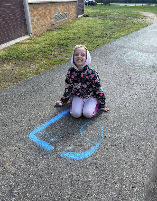 little girl sitting on ground with chalk