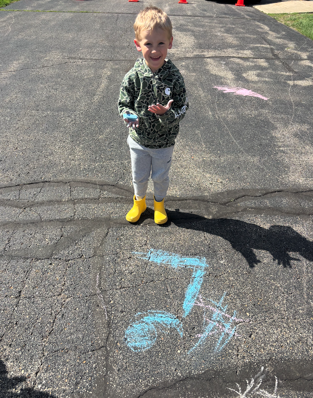 little boy standing on pavement with chalk