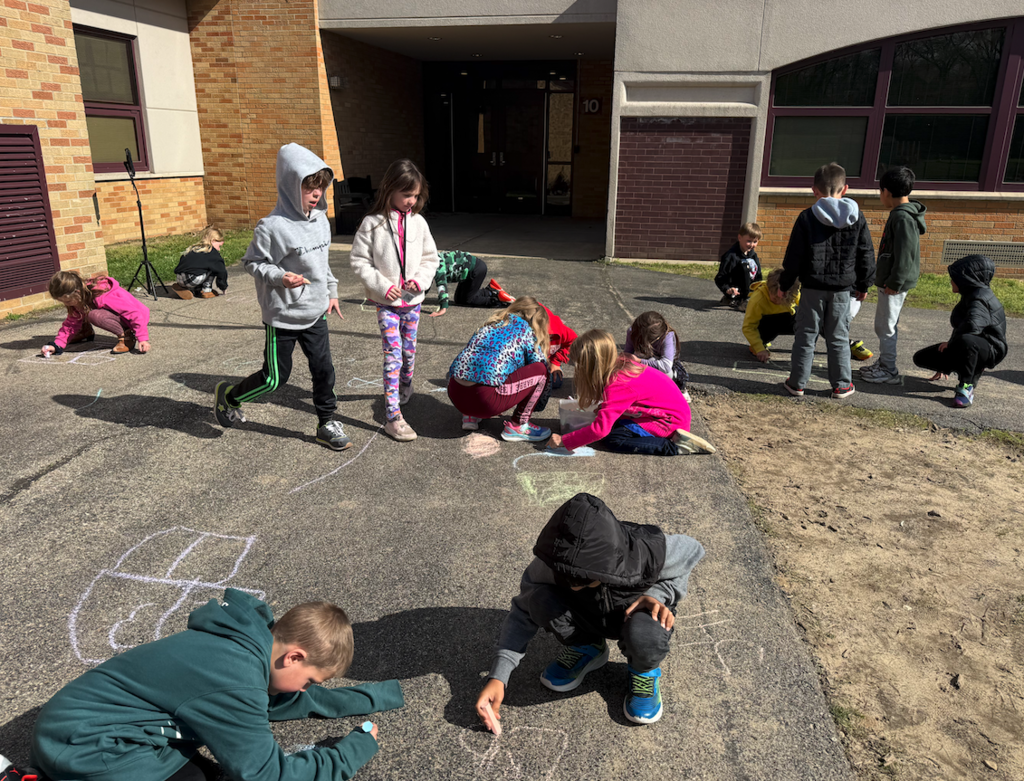 children standing outside on pavement drawing with chalk