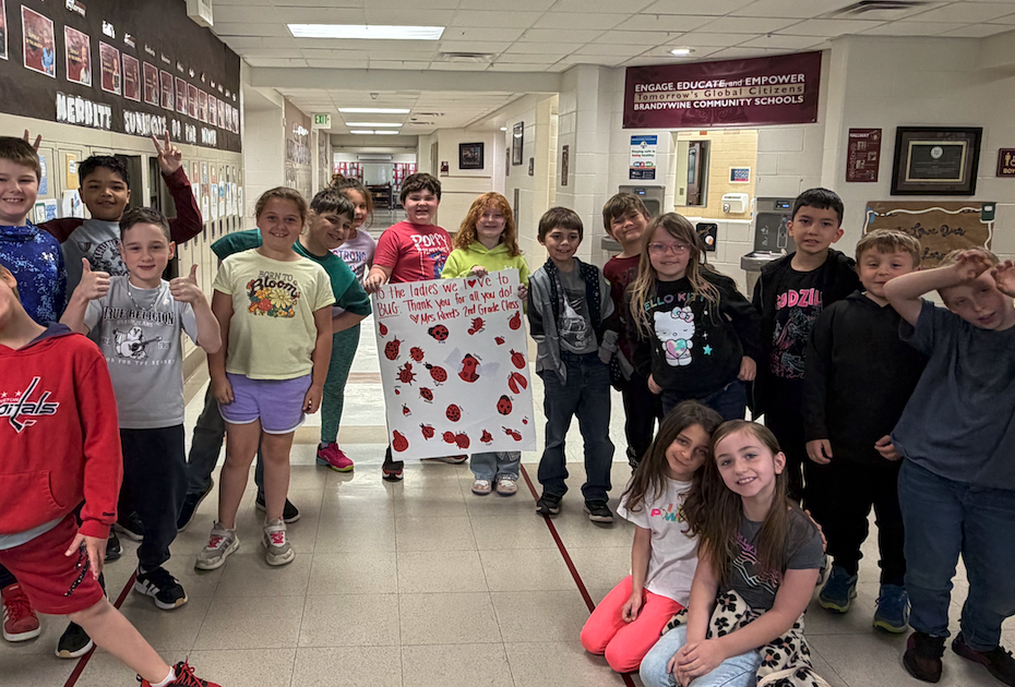 class standing in hallway holding up sign with bugs