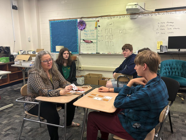 students learning a card game with teacher at desks