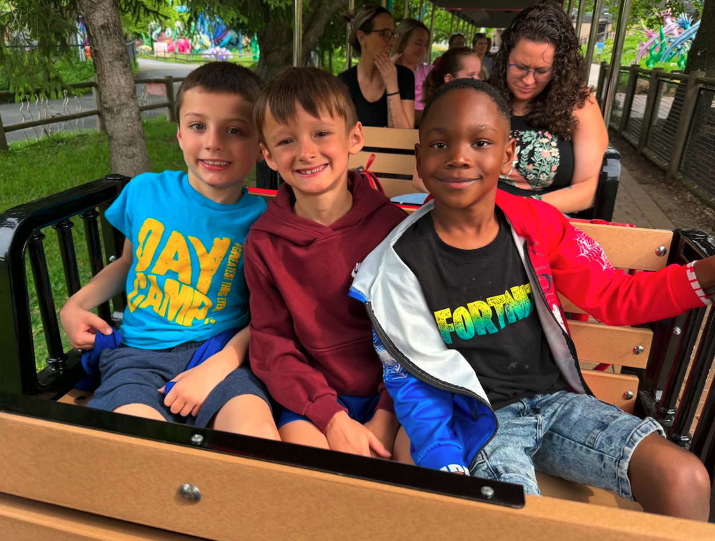 three students riding a train at the zoo