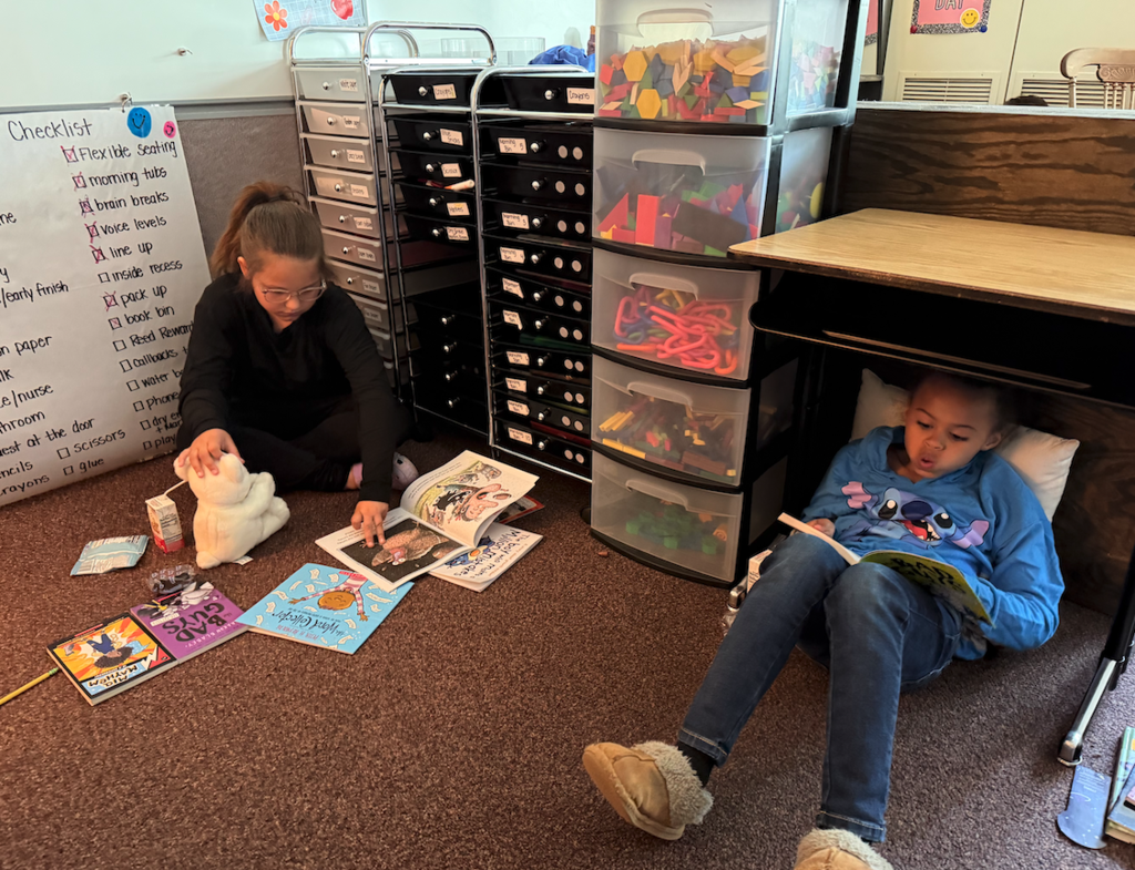 two girls laying on the floor reading