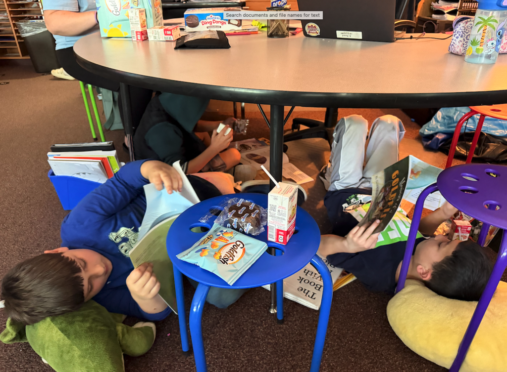two boys laying on the floor reading