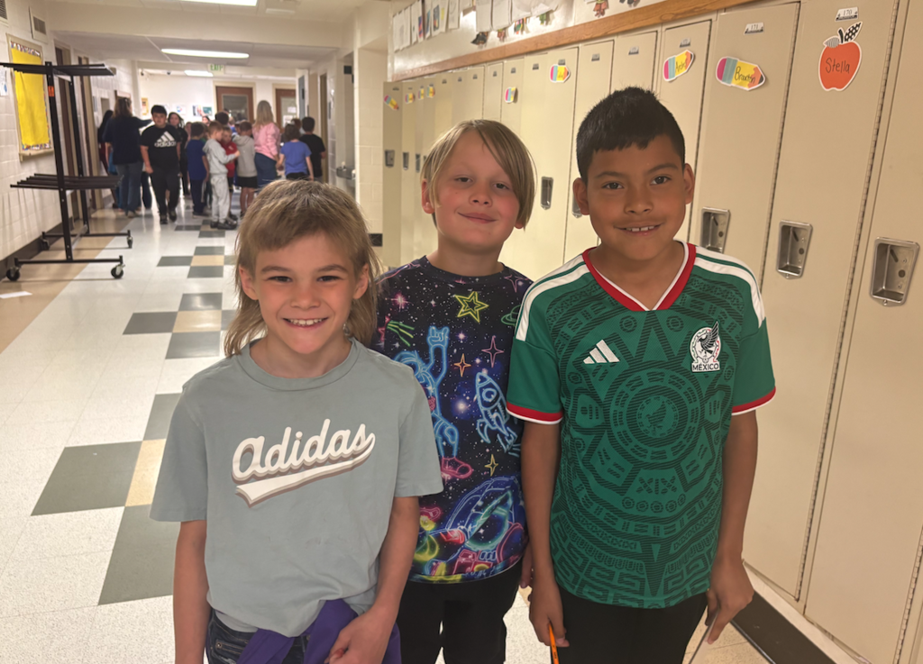 three boys smiling at camera in the hallway