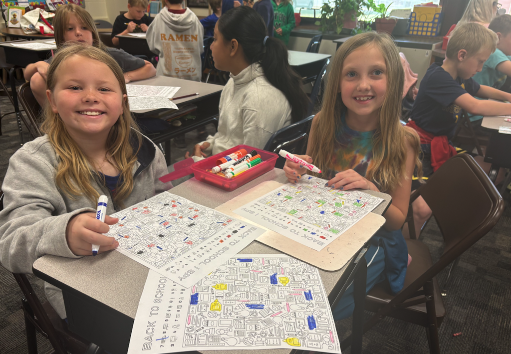 two girls sitting at desk coloring