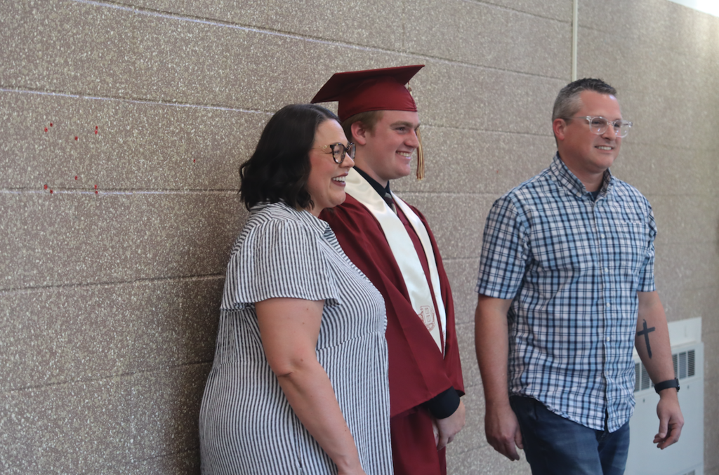 graduate with his parents smiling