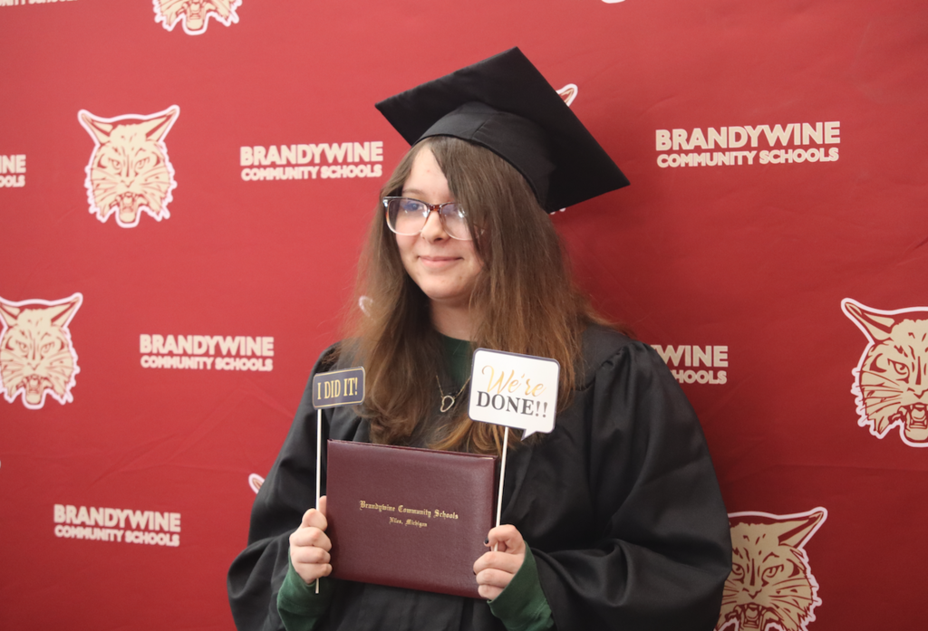 female graduate holding her diploma up in front of Brandywine backdrop