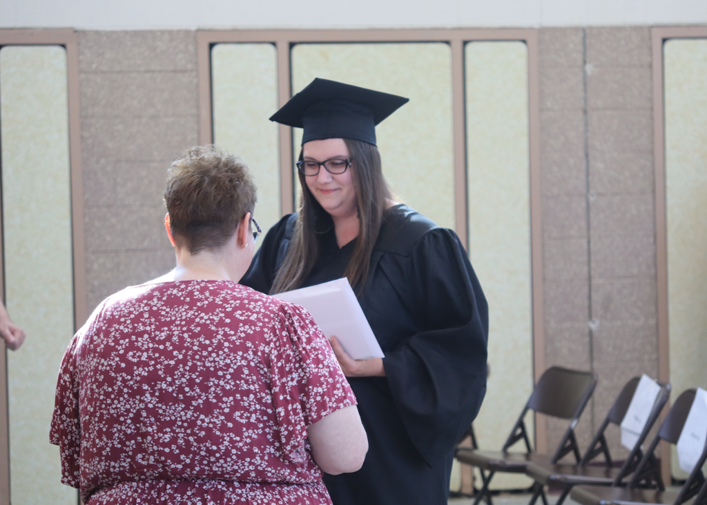 female graduate receiving diploma from teacher