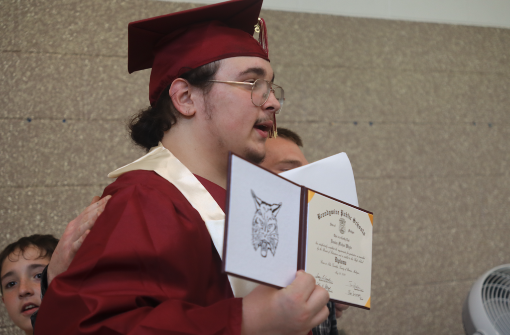 graduate holding diploma up