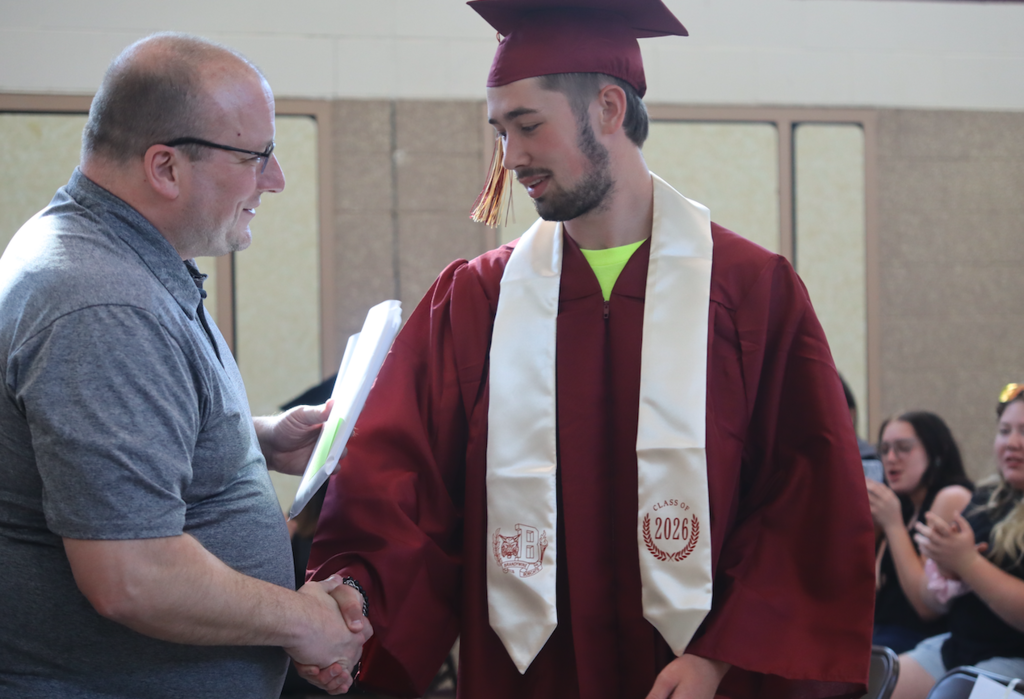 graduate receiving diploma from teacher