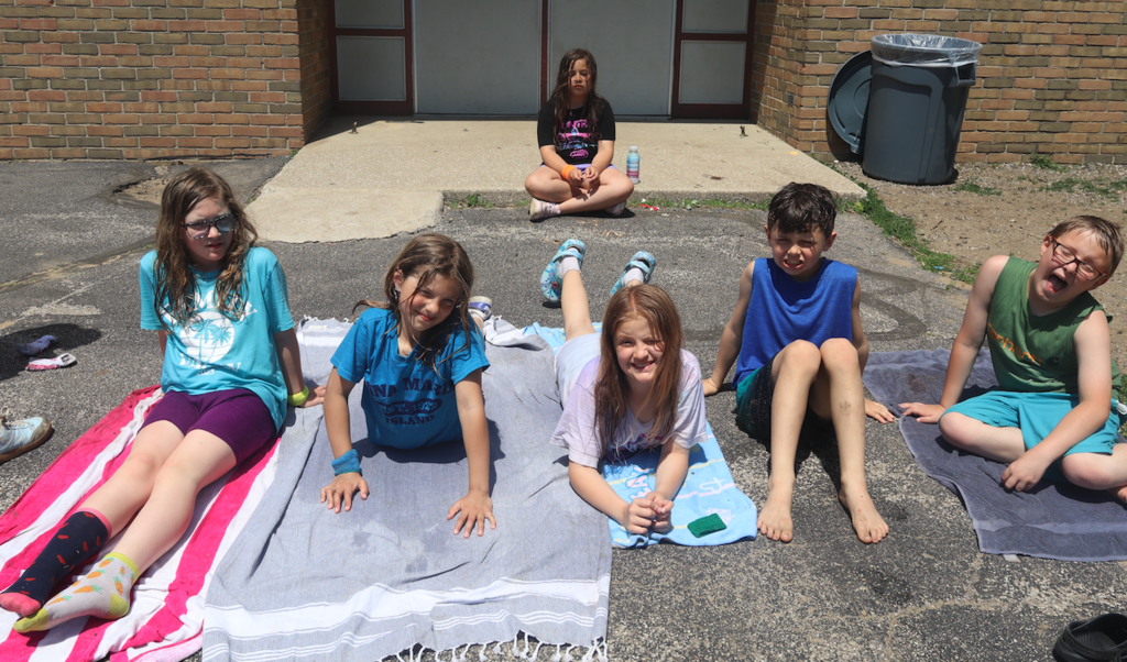 group of kids sitting on the pavement outside