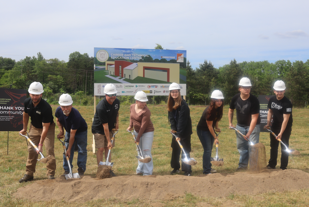 group of students and instructors holding shovels and wearing hard hats