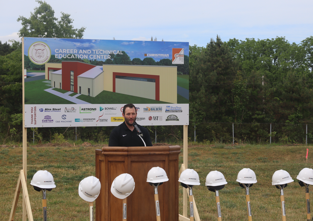 Kirk Shafer speaking at groundbreaking with hard hats and shovels in front of them