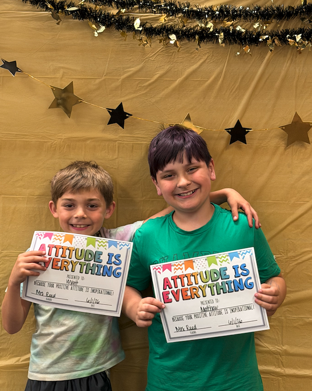 two boys holding certificates for awards