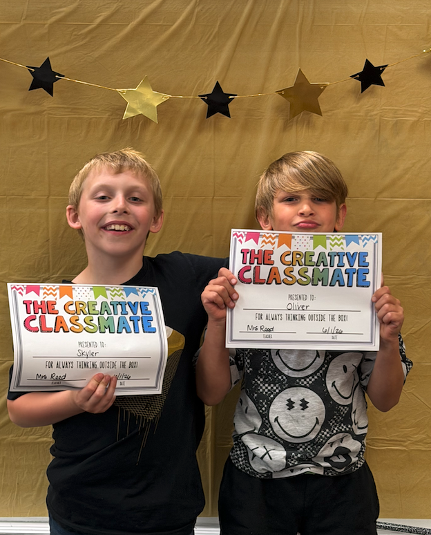 two boys holding certificates for awards
