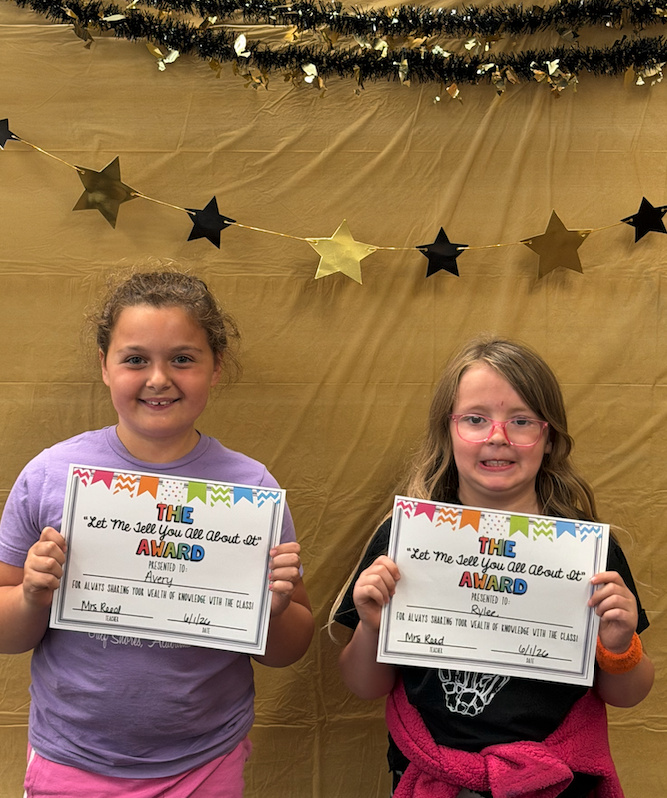 two girls holding certificates for awards