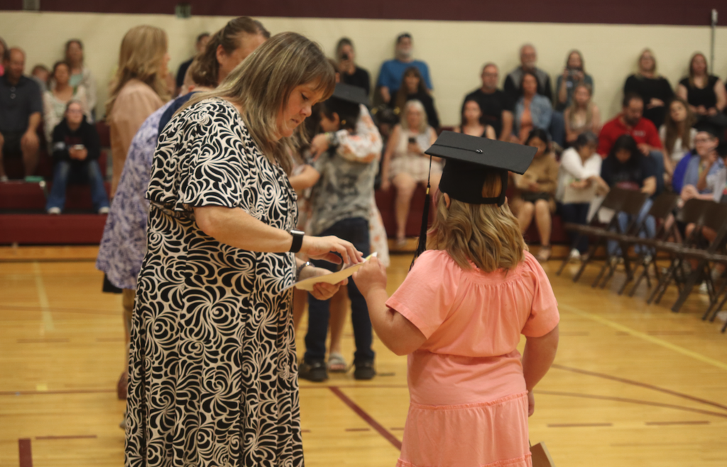 young girl getting certificate from teacher