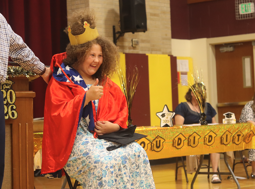 girl with big hair wearing crown and cape, giving thumbs up