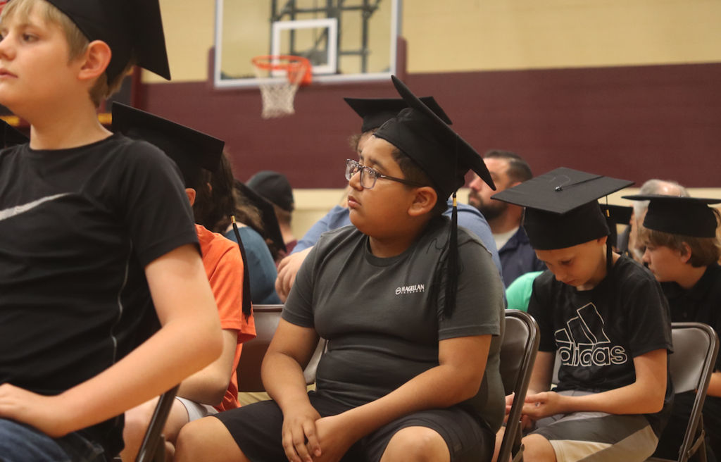 young boy sitting in graduation with hat on