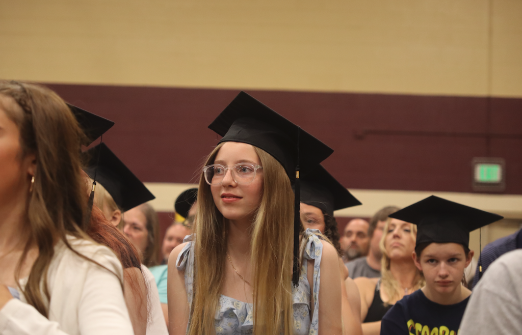 young girl sitting in the crowd with graduation hat on