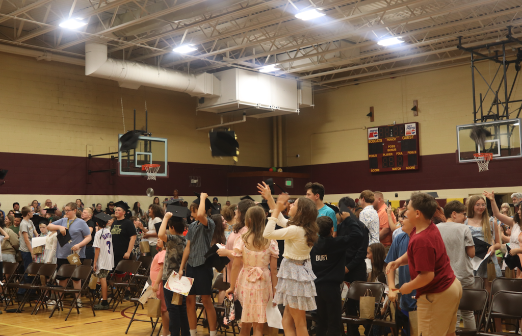 graduates throwing hats in gymnasium