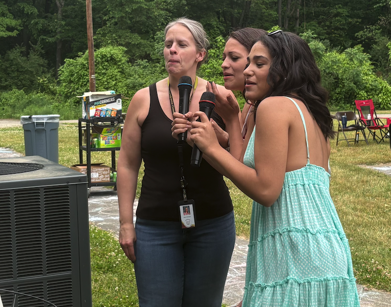 three people doing karaoke outside