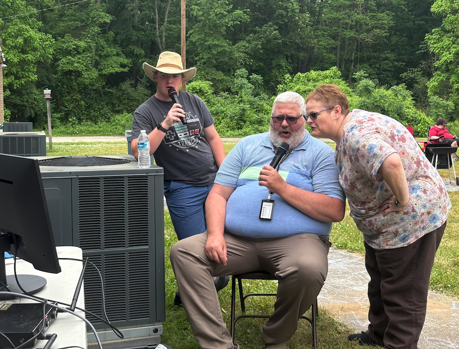 three people doing karaoke outside 