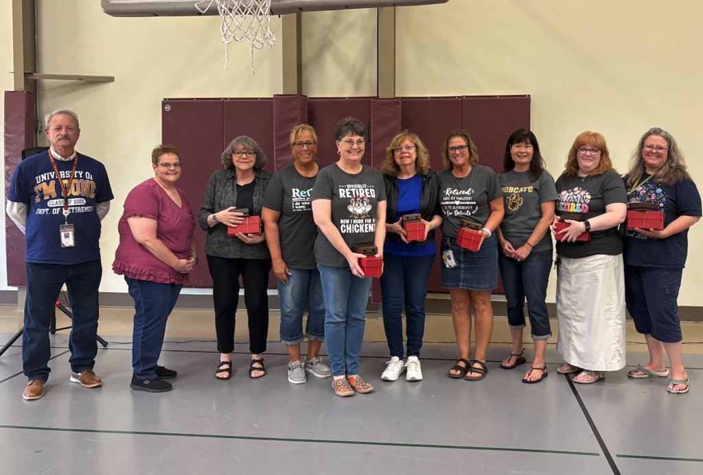 ten retirees standing in the gym with their bells and pins