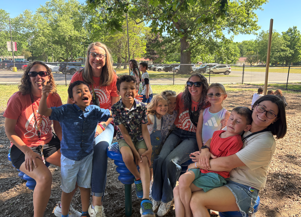 four teachers with a group of students on the playground