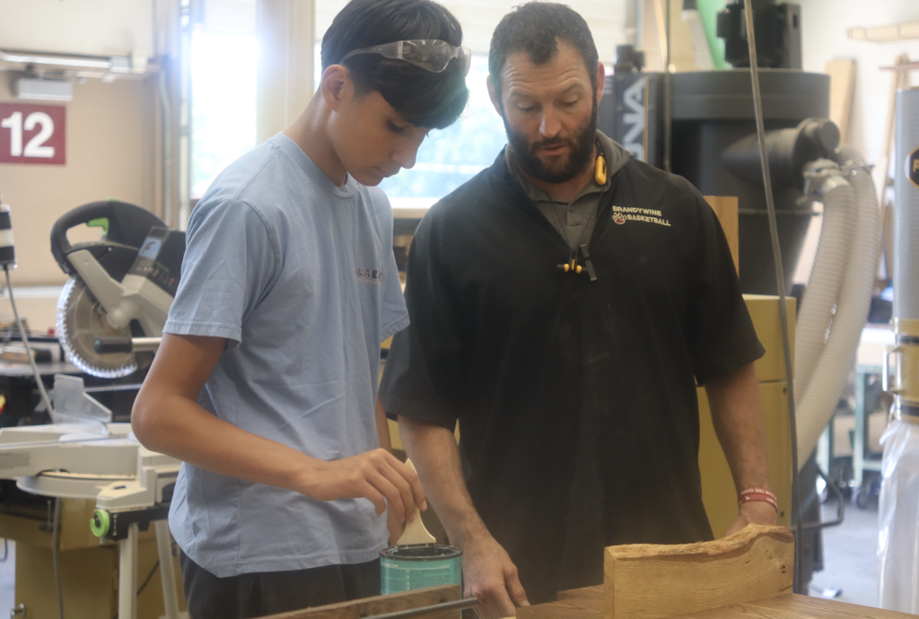 teacher looking at woodshop project with student